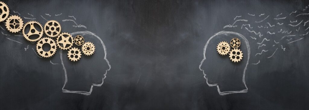 Concept of neurodivergent brain from wooden gears on two head silhouettes on blackboard