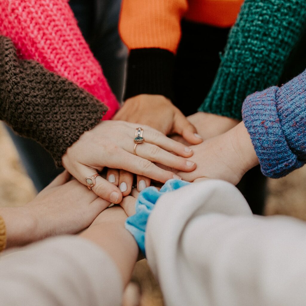A cropped image of a circle of people with their hands stacked
