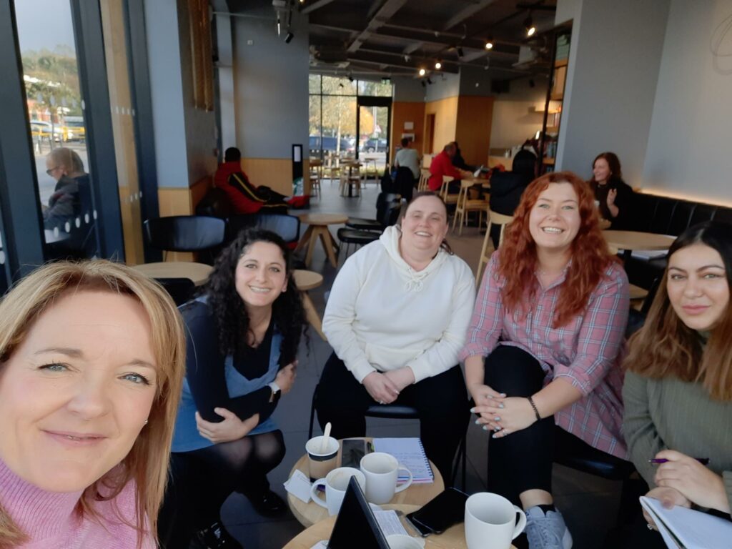 Wellbeing College staff smiling at camera in a cafe, Jayne Simner, Chiara Barbaro, Gemma Osborne and Klaudia Lepska